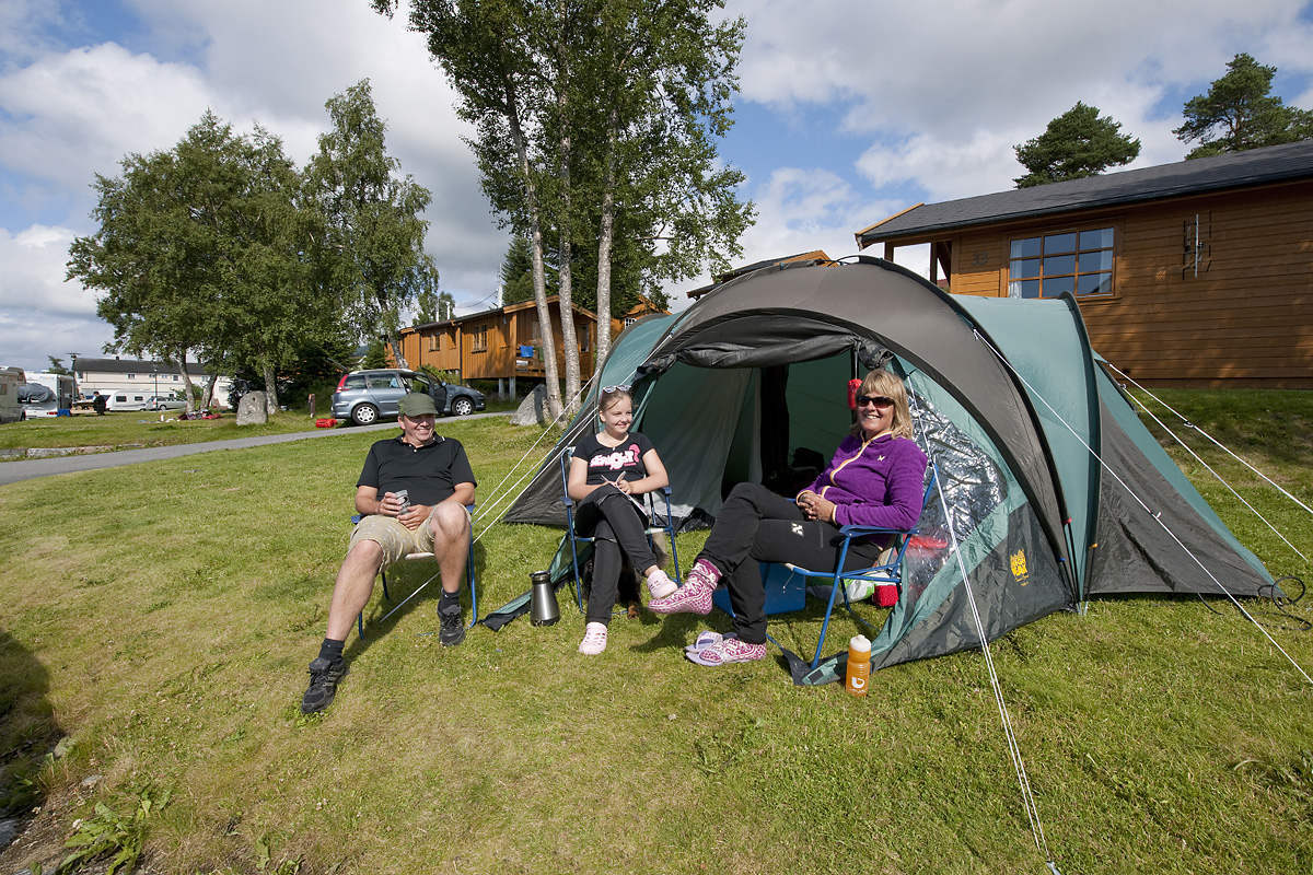 Folk som sitter ved et telt på en campingplass